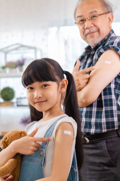 Family-health-safety Child and elderly man showing bandages on their arms after vaccination
