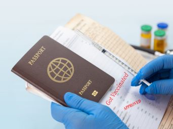 Travel-vaccinations Passport and vaccination documents with gloved hands holding a syringe